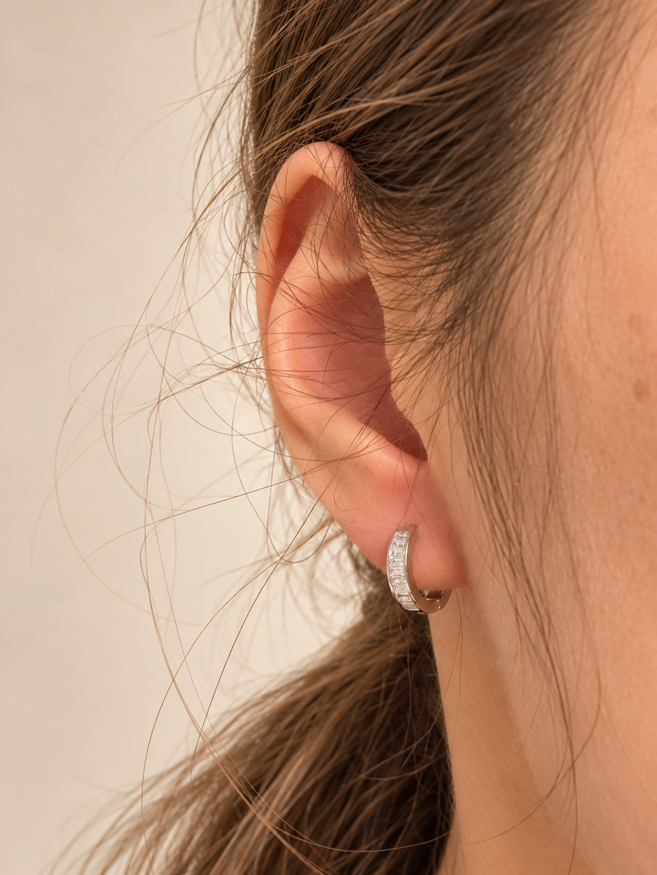 Close-up of baguette zirconia hoop earrings worn on the ear